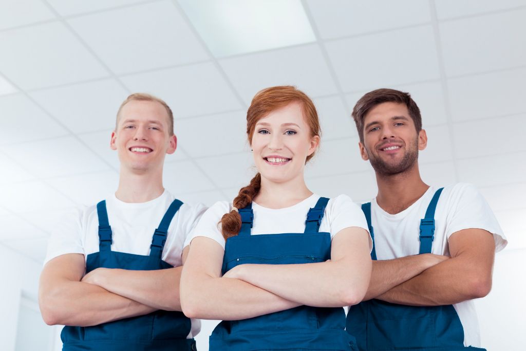 Group of three people with overalls on and arms crossed